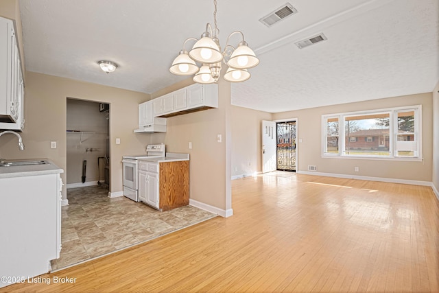 kitchen featuring visible vents, white range with electric cooktop, light countertops, an inviting chandelier, and a sink