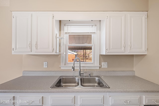 kitchen with white cabinetry, light countertops, and a sink