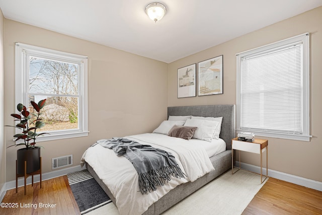 bedroom with wood finished floors, visible vents, and baseboards