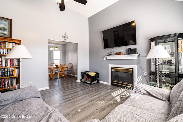 living room featuring a glass covered fireplace, baseboards, a ceiling fan, and wood finished floors