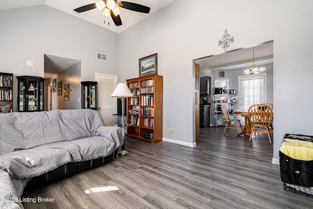 living area featuring visible vents, baseboards, ceiling fan with notable chandelier, high vaulted ceiling, and dark wood-style flooring