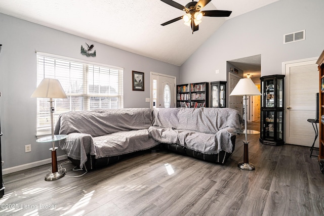 living area with visible vents, high vaulted ceiling, a ceiling fan, wood finished floors, and baseboards