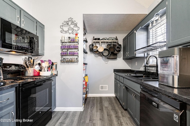 kitchen with visible vents, a sink, black appliances, a textured ceiling, and dark countertops