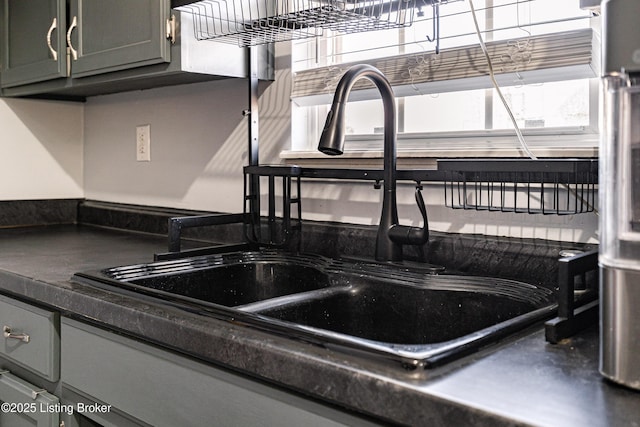 interior details featuring a sink, dark countertops, and gray cabinets