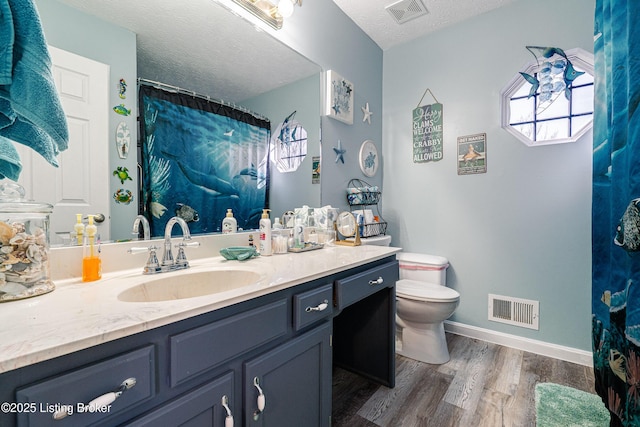 full bathroom featuring visible vents, toilet, a textured ceiling, and wood finished floors