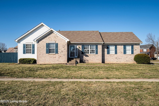 ranch-style home with brick siding, roof with shingles, a front yard, and fence