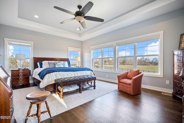 bedroom with dark wood-style floors, recessed lighting, a raised ceiling, and baseboards