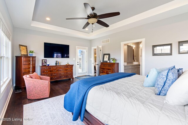 bedroom featuring visible vents, a tray ceiling, and wood finished floors