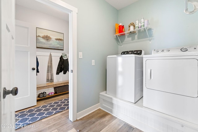 laundry area featuring laundry area, wood finished floors, baseboards, and washing machine and clothes dryer