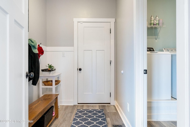 mudroom featuring light wood-style flooring, separate washer and dryer, and wainscoting