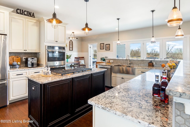 kitchen with dark wood-style flooring, a sink, a large island, appliances with stainless steel finishes, and backsplash