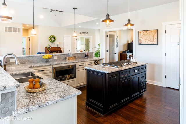 kitchen featuring visible vents, a sink, appliances with stainless steel finishes, lofted ceiling, and dark cabinets