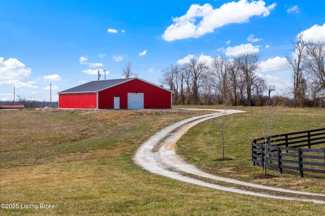 view of pole building with a yard, fence, and driveway