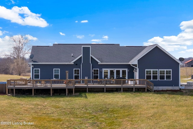 rear view of house featuring a deck, a shingled roof, and a yard