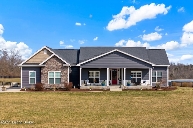 craftsman-style house with stone siding, a porch, and a front lawn