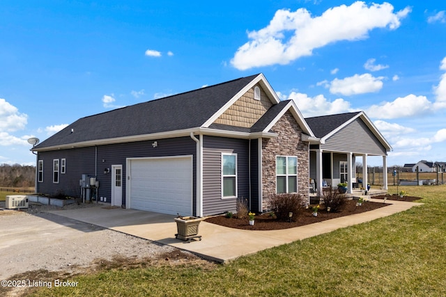 view of home's exterior with a porch, a yard, a garage, stone siding, and driveway