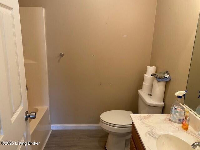 bathroom with baseboards, toilet, wood finished floors, and vanity