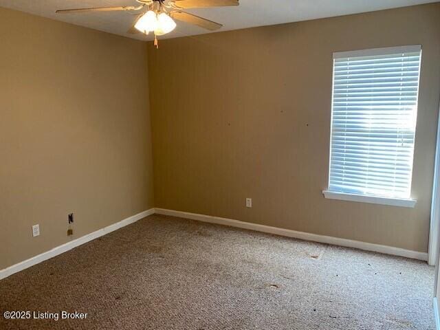 carpeted empty room with a ceiling fan and baseboards