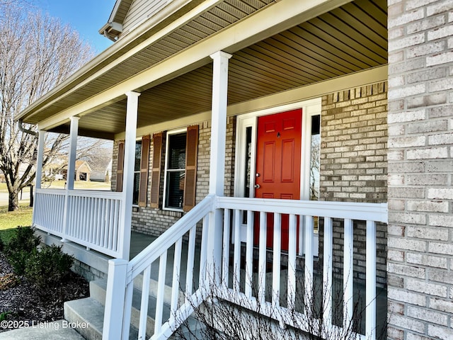 view of exterior entry with covered porch and brick siding