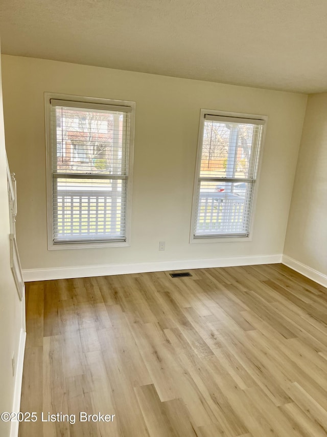 empty room with visible vents, baseboards, and wood finished floors