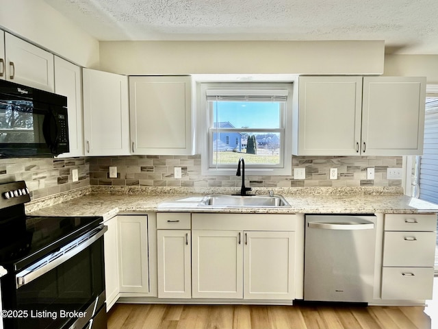 kitchen featuring a sink, stainless steel appliances, light wood finished floors, and white cabinetry