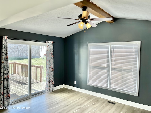 empty room with a textured ceiling, vaulted ceiling with beams, baseboards, and wood finished floors