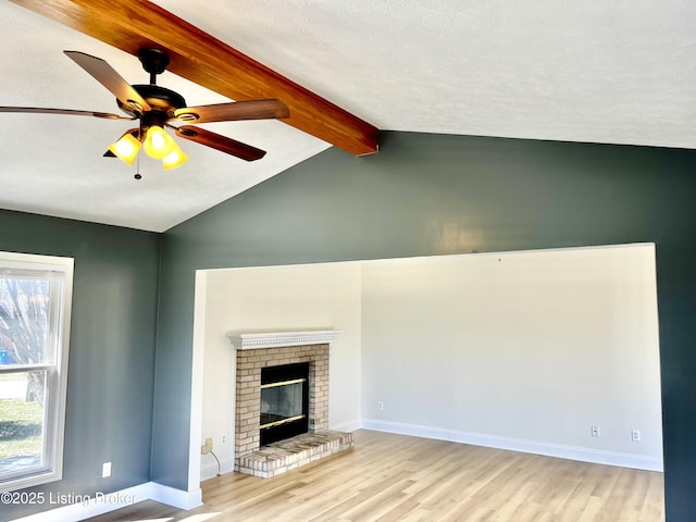 unfurnished living room with a ceiling fan, wood finished floors, baseboards, vaulted ceiling with beams, and a fireplace