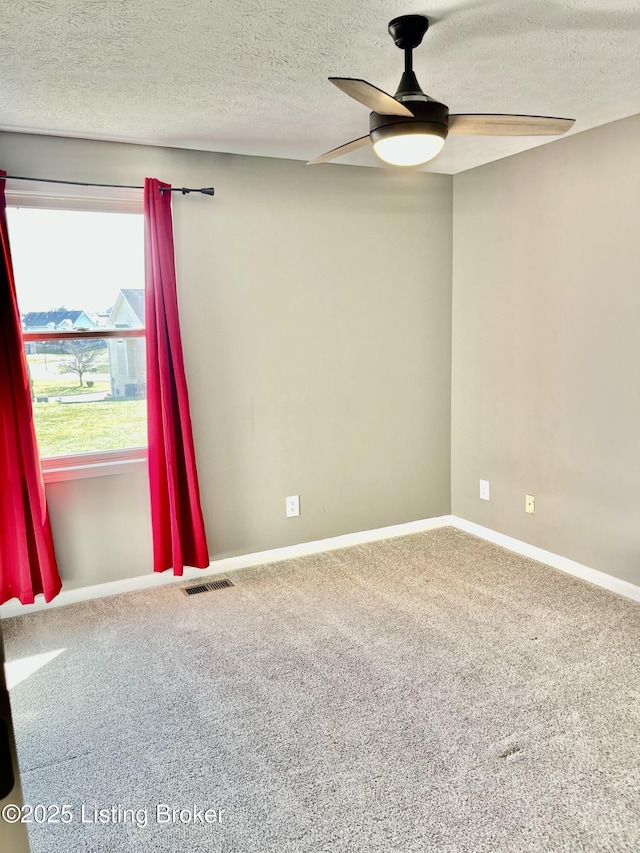 carpeted empty room with visible vents, baseboards, a textured ceiling, and a ceiling fan