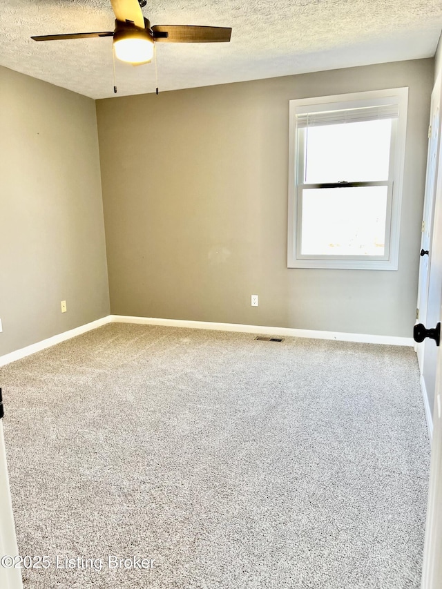 carpeted spare room featuring visible vents, a textured ceiling, baseboards, and a ceiling fan