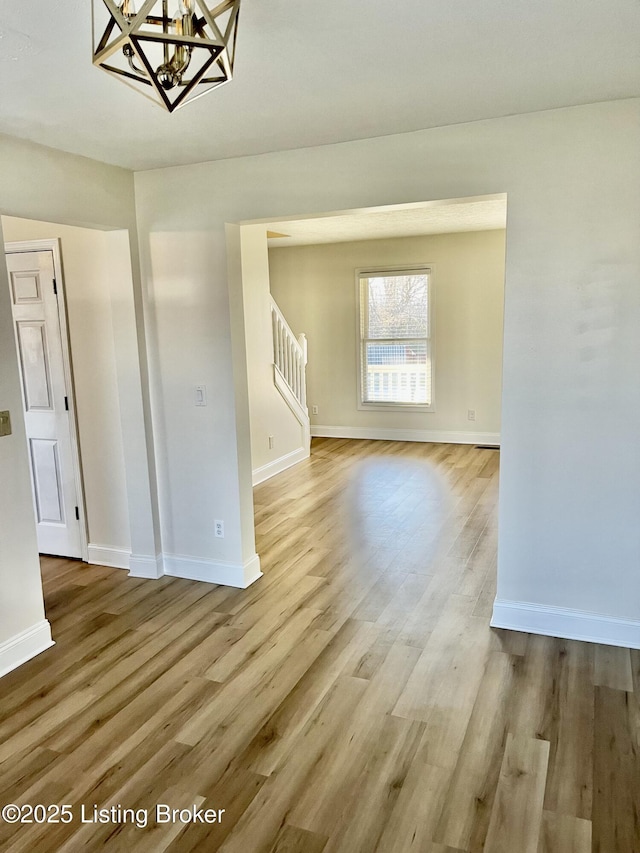 unfurnished dining area with baseboards, wood finished floors, and stairs