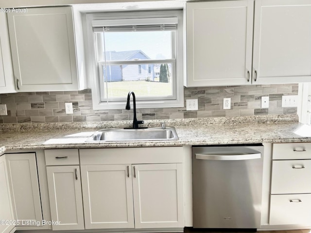 kitchen featuring decorative backsplash, white cabinets, dishwasher, and a sink