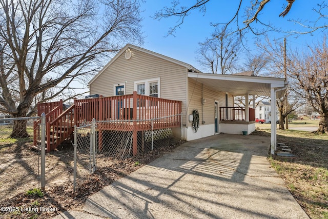 back of property with a deck, an attached carport, fence, and driveway