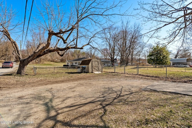 view of yard featuring an outbuilding, driveway, a storage shed, and fence