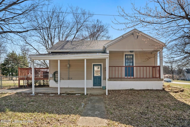 view of front facade featuring covered porch, a shingled roof, and fence