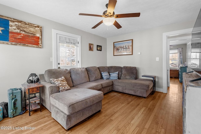 living room with light wood finished floors, baseboards, and ceiling fan