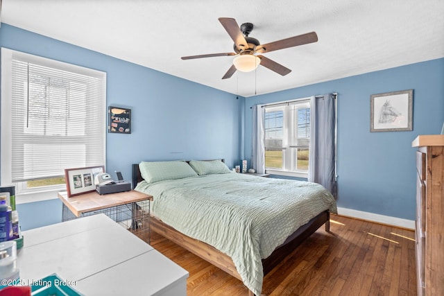 bedroom with a ceiling fan, baseboards, and hardwood / wood-style flooring