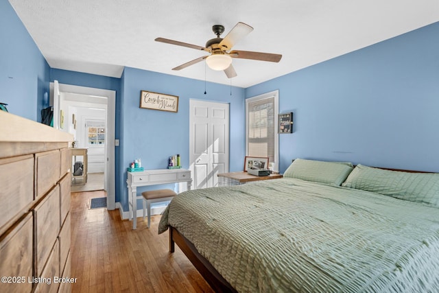 bedroom with hardwood / wood-style flooring, visible vents, baseboards, and ceiling fan