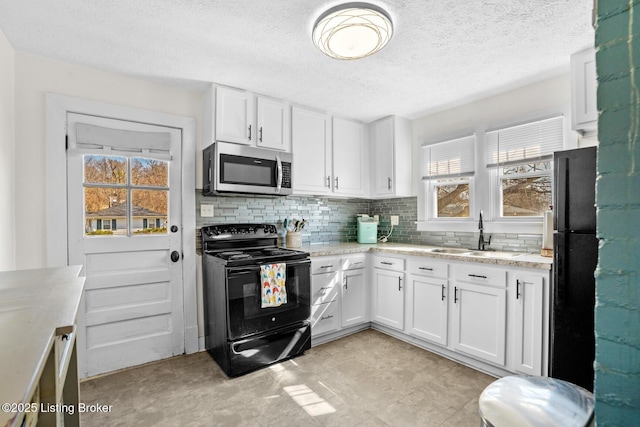 kitchen featuring decorative backsplash, white cabinetry, black appliances, and a sink