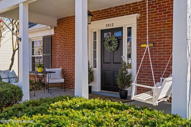 entrance to property with brick siding and a porch