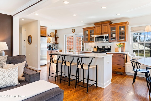 kitchen with open floor plan, a kitchen bar, appliances with stainless steel finishes, brown cabinetry, and a sink