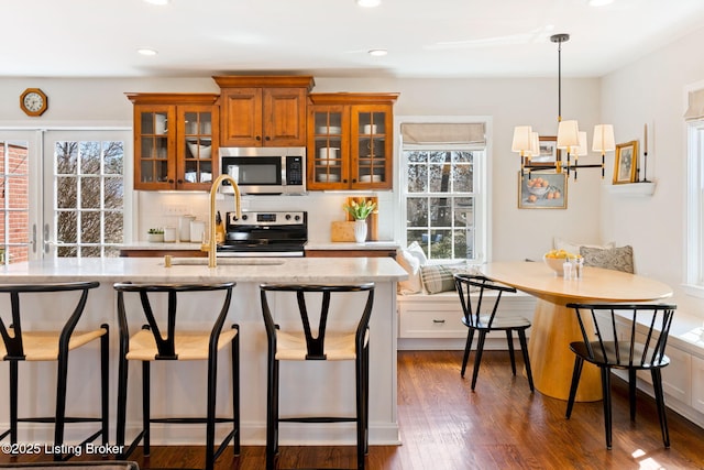 kitchen with a kitchen bar, plenty of natural light, breakfast area, appliances with stainless steel finishes, and brown cabinetry