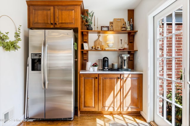 kitchen with open shelves, stainless steel fridge with ice dispenser, visible vents, and a healthy amount of sunlight