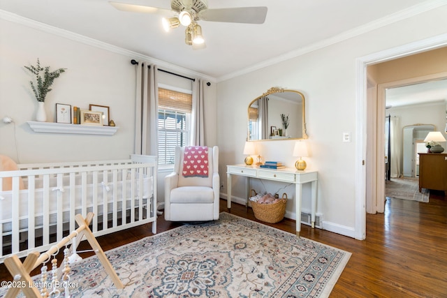 bedroom with a crib, baseboards, wood finished floors, and ornamental molding