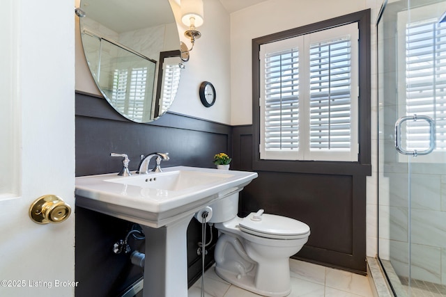 full bath featuring toilet, a stall shower, and wainscoting