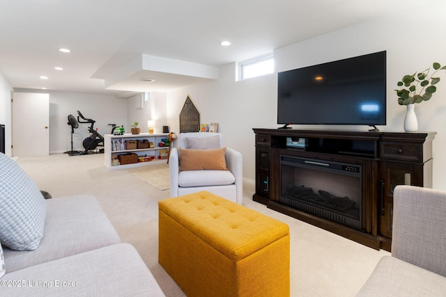 carpeted living area featuring recessed lighting, visible vents, and a glass covered fireplace