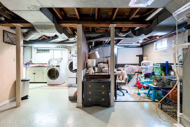 below grade area with washer and clothes dryer, baseboards, and a sink