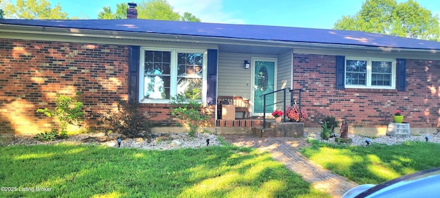 view of front of property with a front lawn, brick siding, and a chimney