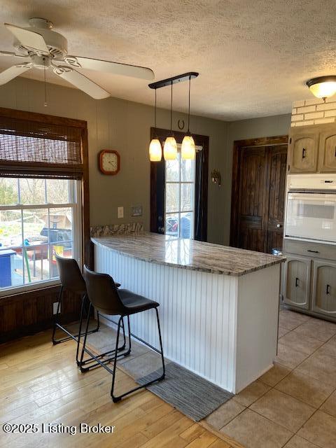 kitchen with white oven, a textured ceiling, a peninsula, and a wealth of natural light