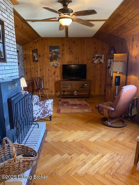 living room with wood walls, ceiling fan, and vaulted ceiling