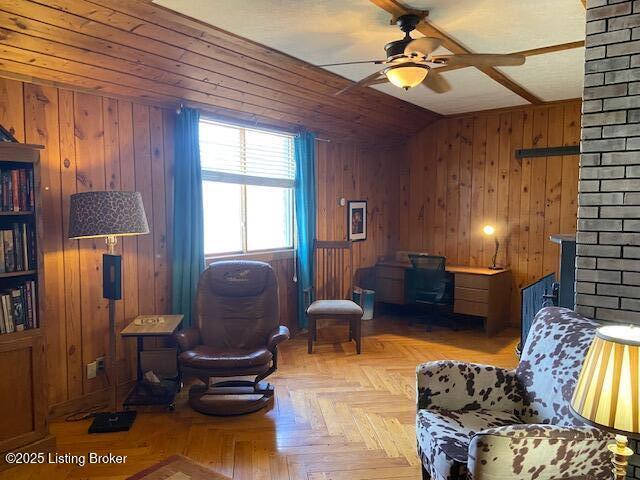 living area with wooden walls, a ceiling fan, and vaulted ceiling